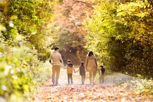 AECORD family lifestyle image of parents and children walking down a leafy path in warm sunlight, symbolizing secure and well‑planned family living.