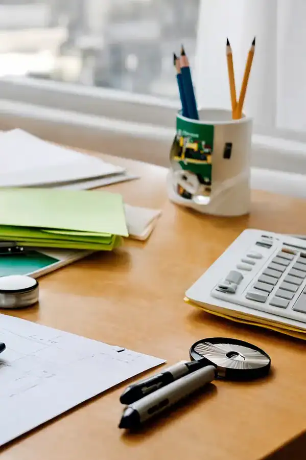 Organized home office desk with computer, calculator, color swatches, notepads, and stationery used for budgeting and project planning.