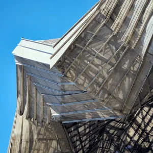 Abstract view of a modern steel and glass building elevation under a blue sky, representing environmentally compliant architecture and MOEF clearance services offered by AECORD.