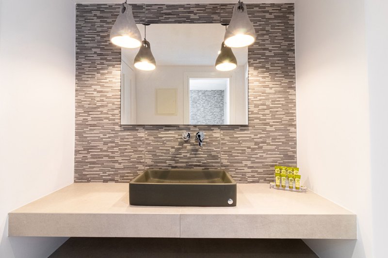 The bathroom of the room with the washbasin, the lights, the mirror and the spacious countertop