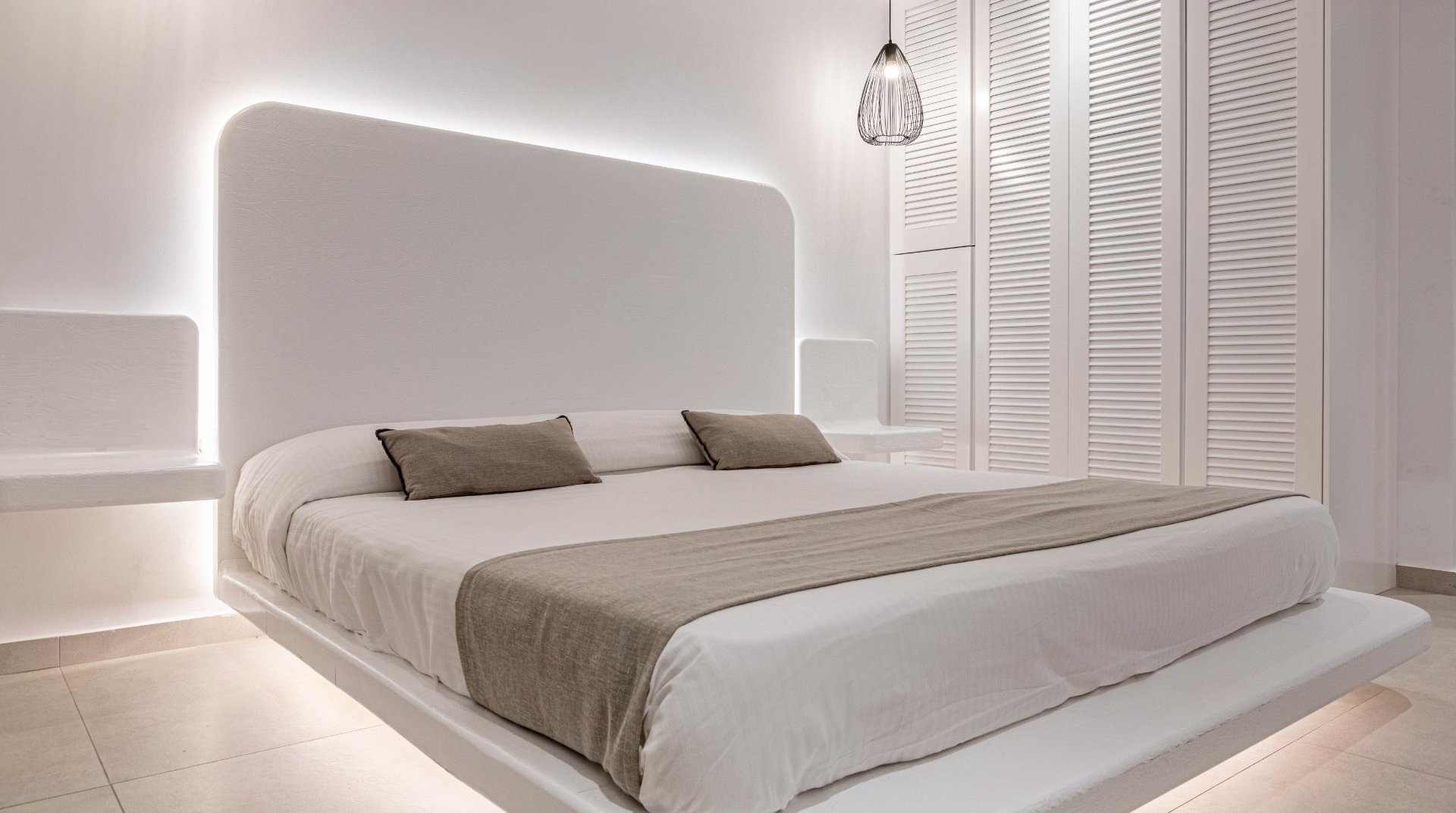 The interior of the room with the bed and the underlights, the modern bedside tables and the closet