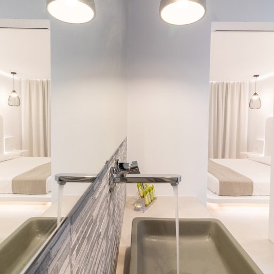 The bathroom of the room with the washbasin, the lights, the mirror and the spacious countertop