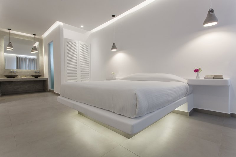 The interior of the suite with the bed, the closet, and in the background the spacious counter with the modern sinks and the huge mirror