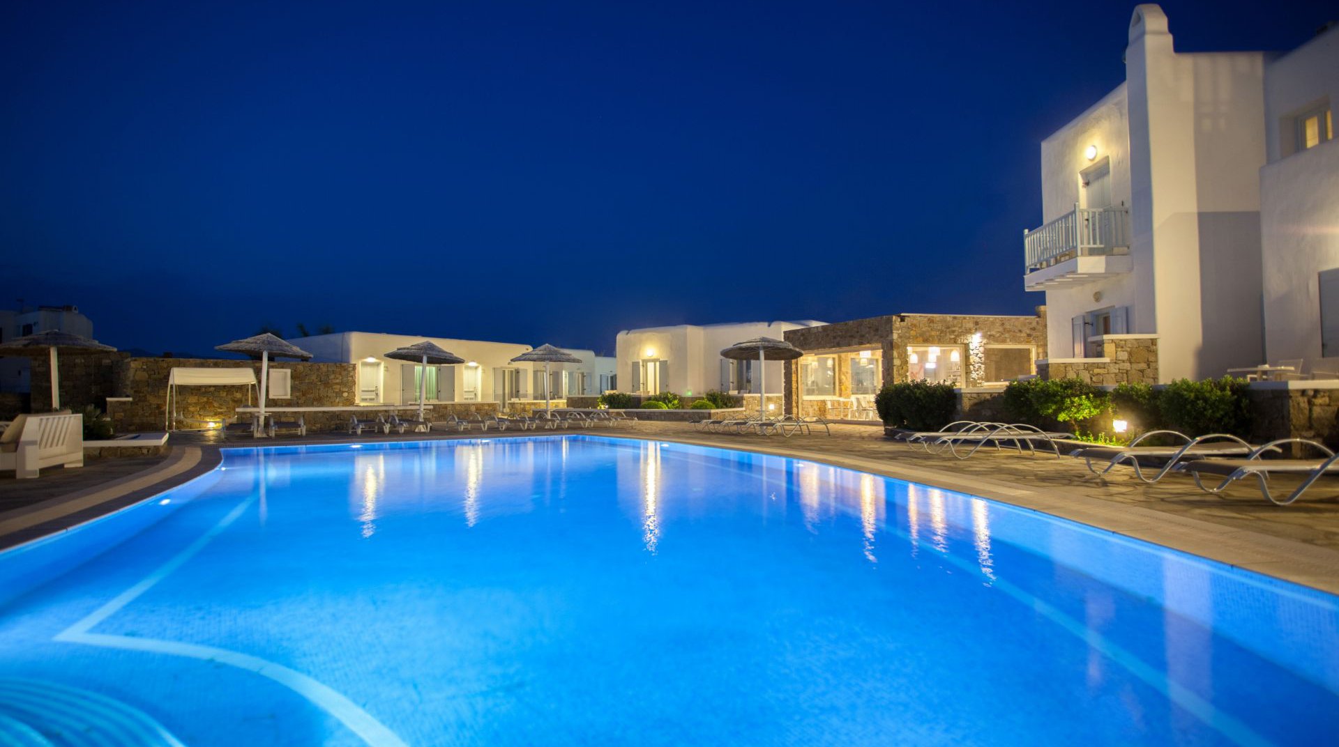 The pool of the Sunset Wing during night time with the suneds and the resort in the background