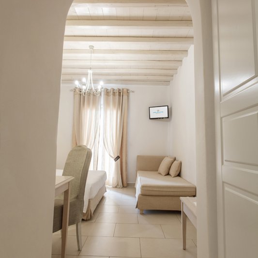 The interior of the room from the hallway coming in, with the single bed and the TV in the background