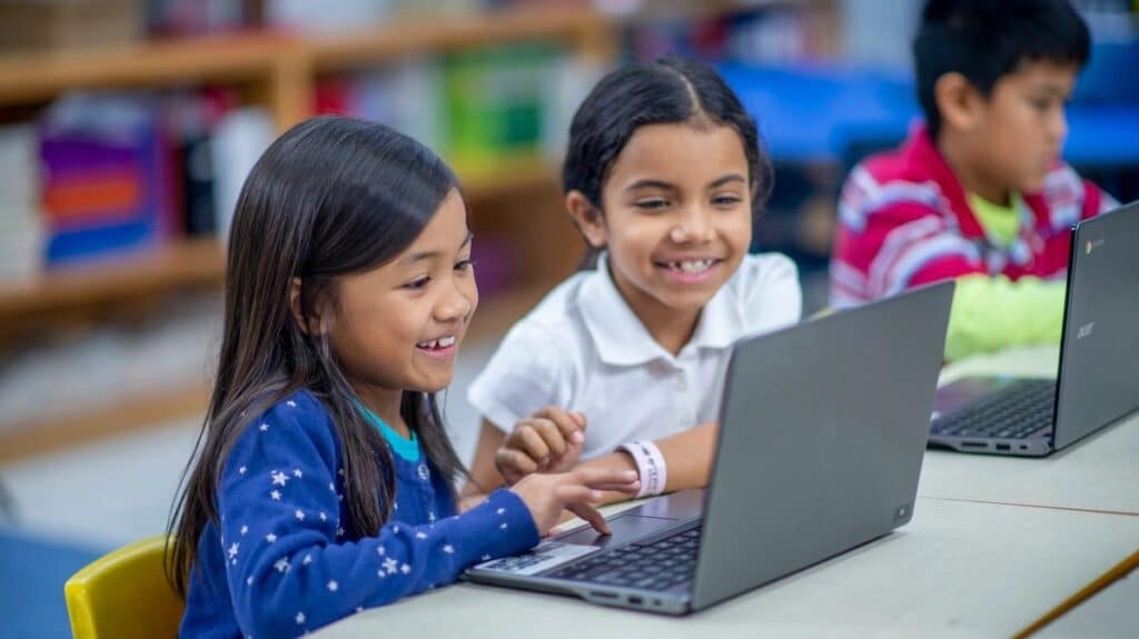 Two elementary school girls working at a laptop in a library