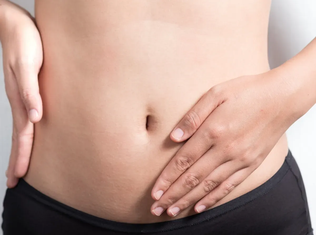 The woman is touching her abdomen.