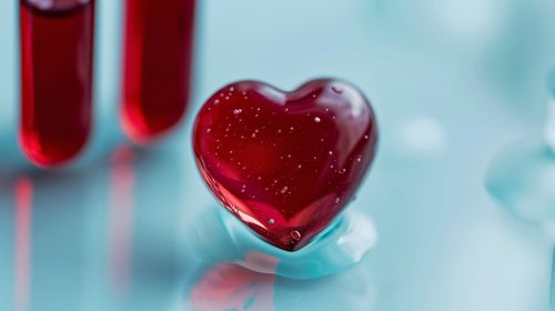 Heart-shaped drop of blood with test tubes in the background