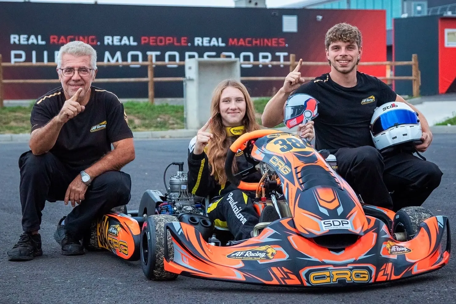 Il team in posa intorno a un kart davanti al box