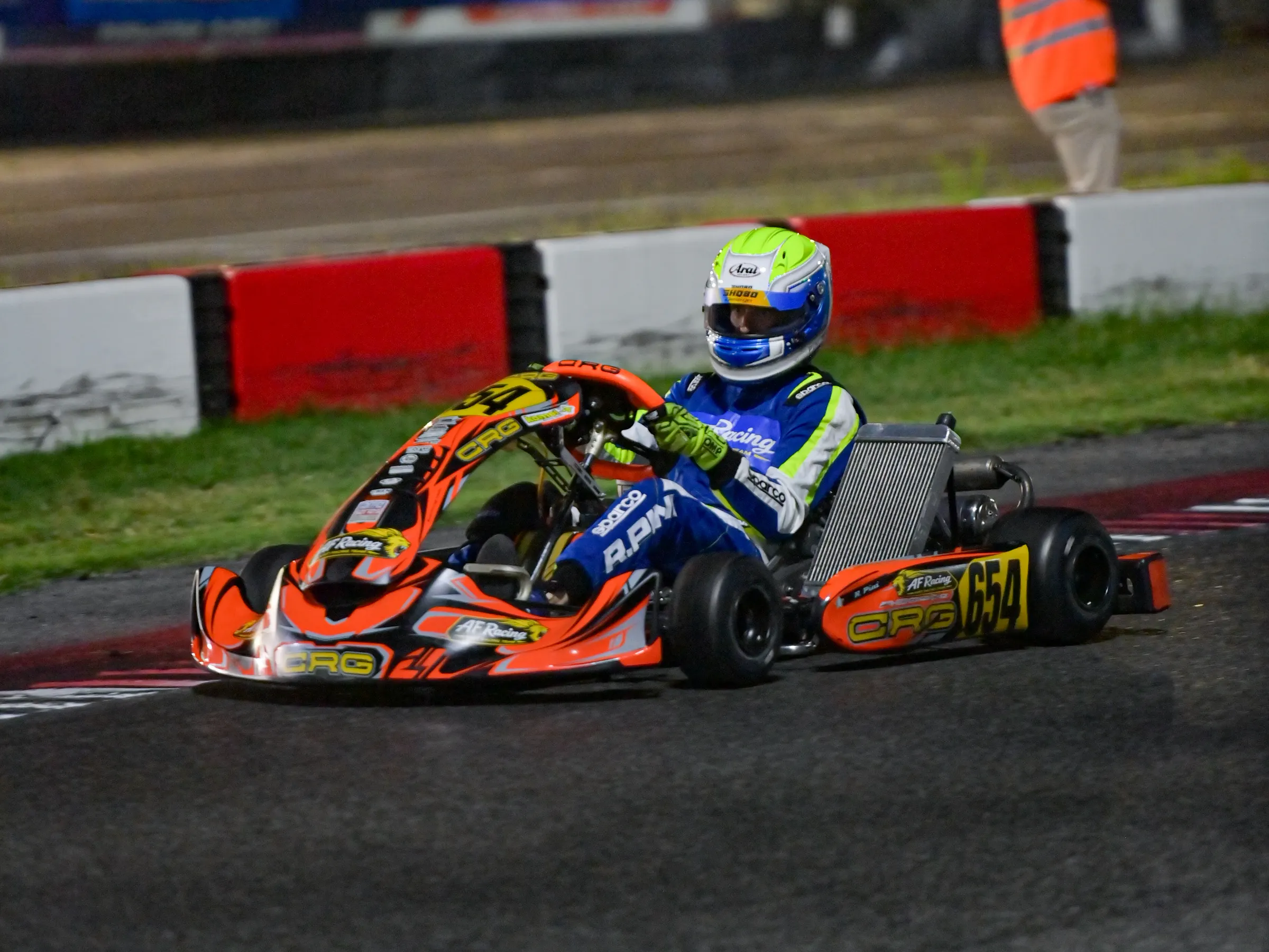Kart arancione in pista in notturna, sotto i riflettori