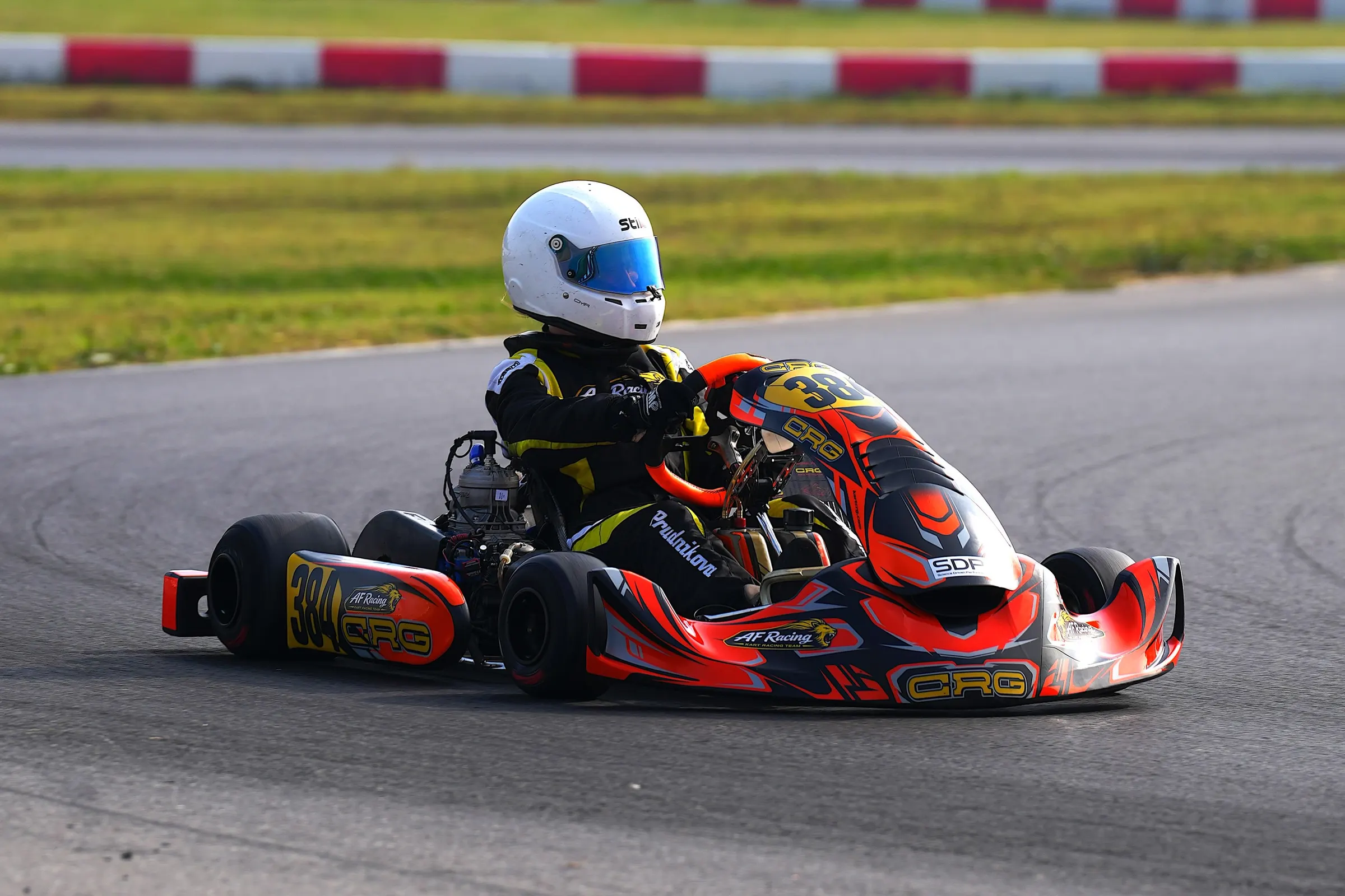 Pilota con casco bianco in curva sul kart arancione