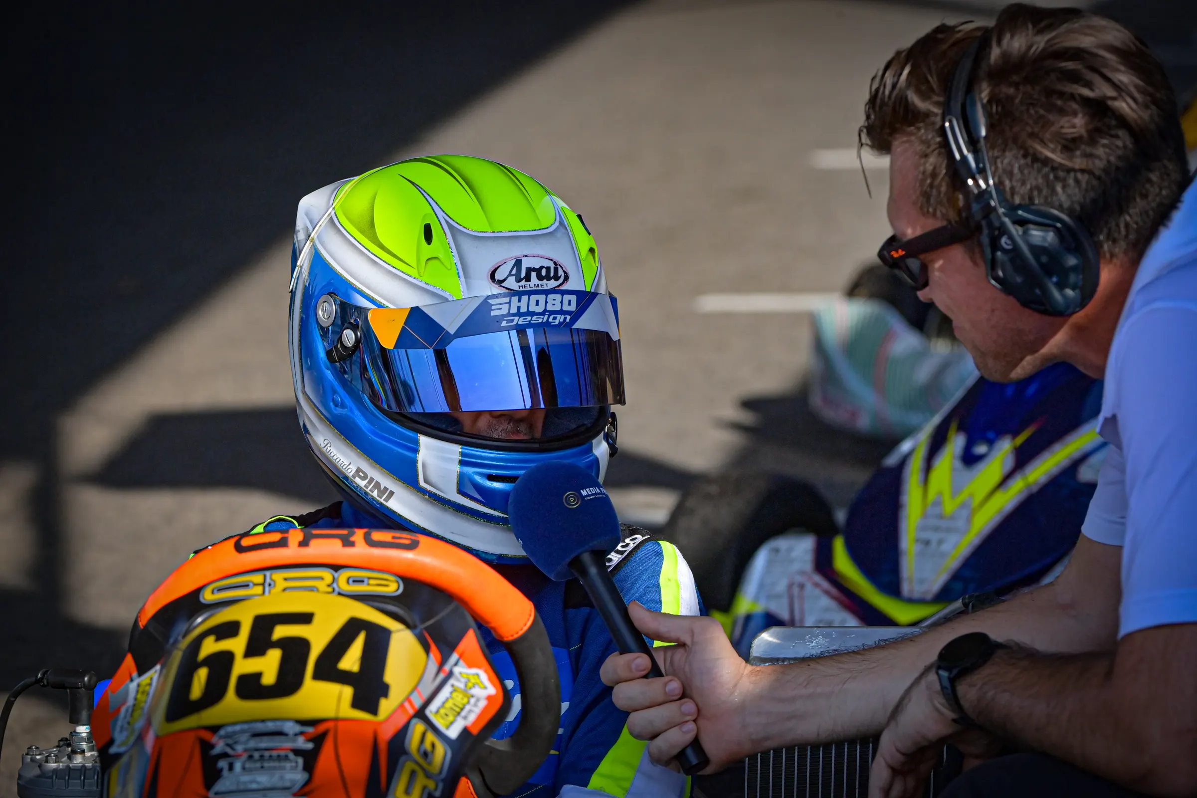 Il pilota del kart 654, col casco, a colloquio con il team manager in cuffia