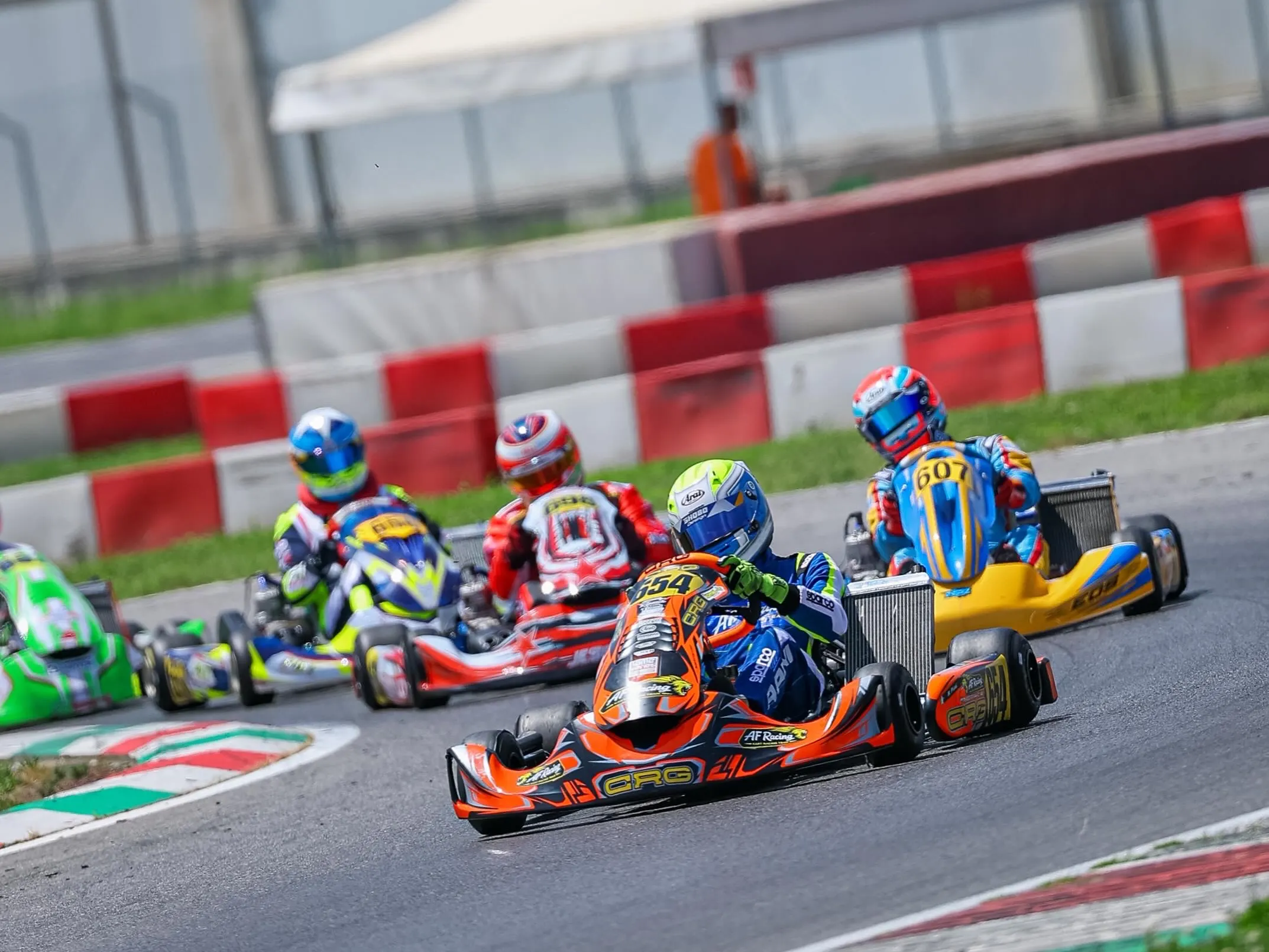 Gruppo di kart in curva, in testa il kart arancione del team
