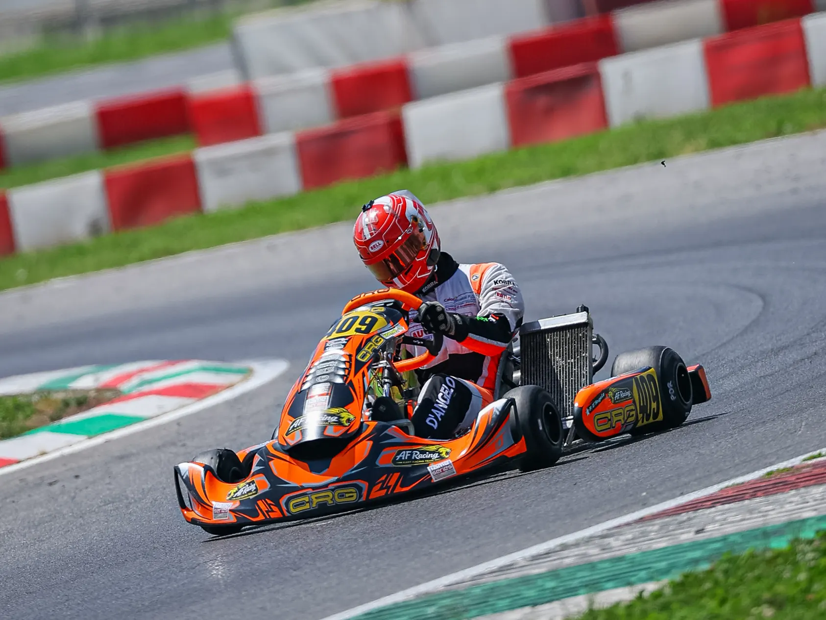 Pilota con casco rosso in piega sul cordolo