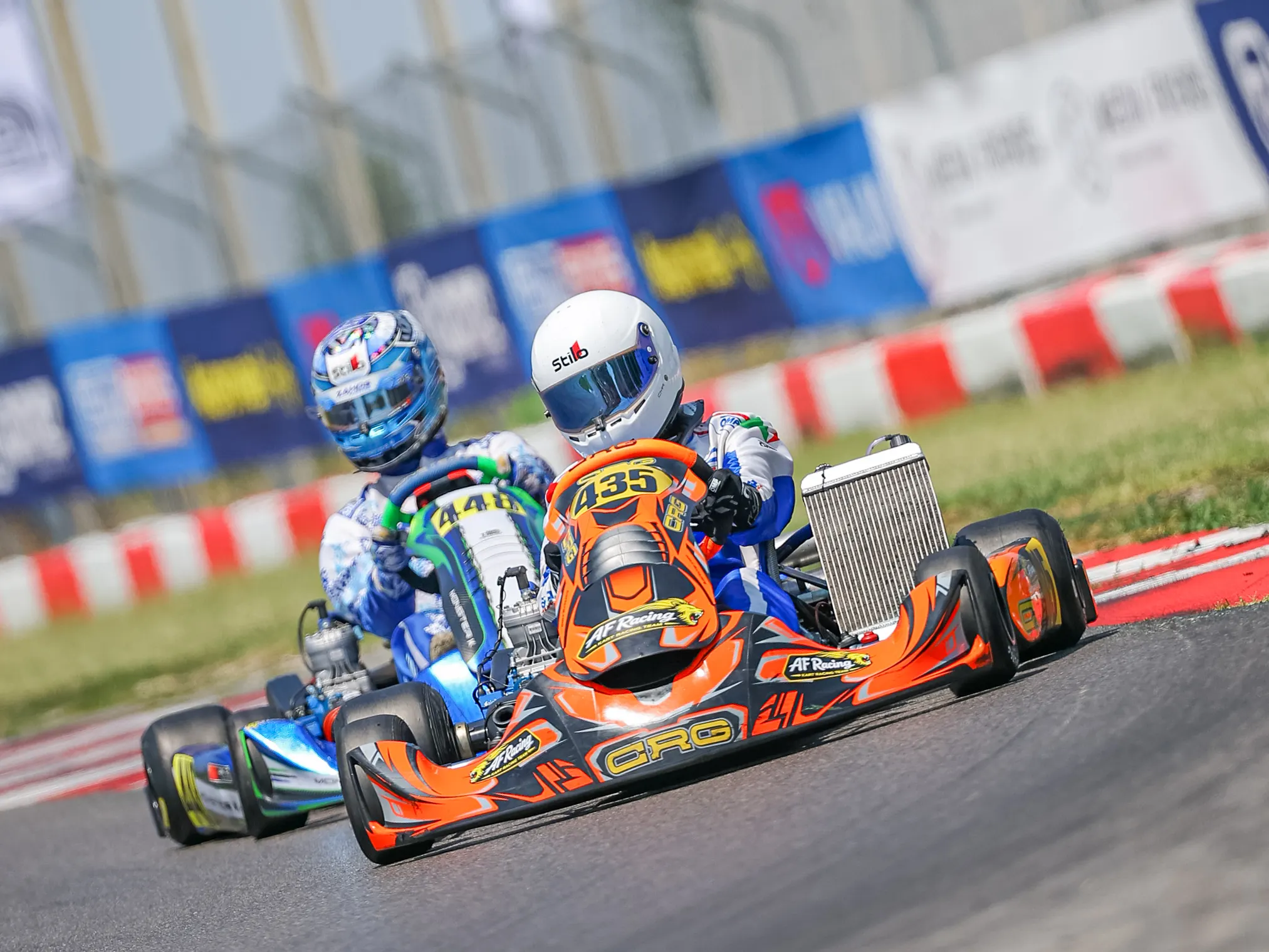 Kart arancione davanti a due kart in curva