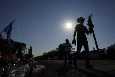 Roberto Marquez coloca una cruz de madera en un monumento conmemorativo improvisado en el sitio en el que las autoridades descubrieron a más de 50 migrantes muertos en un tractocamión abandonado, el 30 de junio de 2022, en San Antonio, Texas. (AP Foto/Eric Gay)
