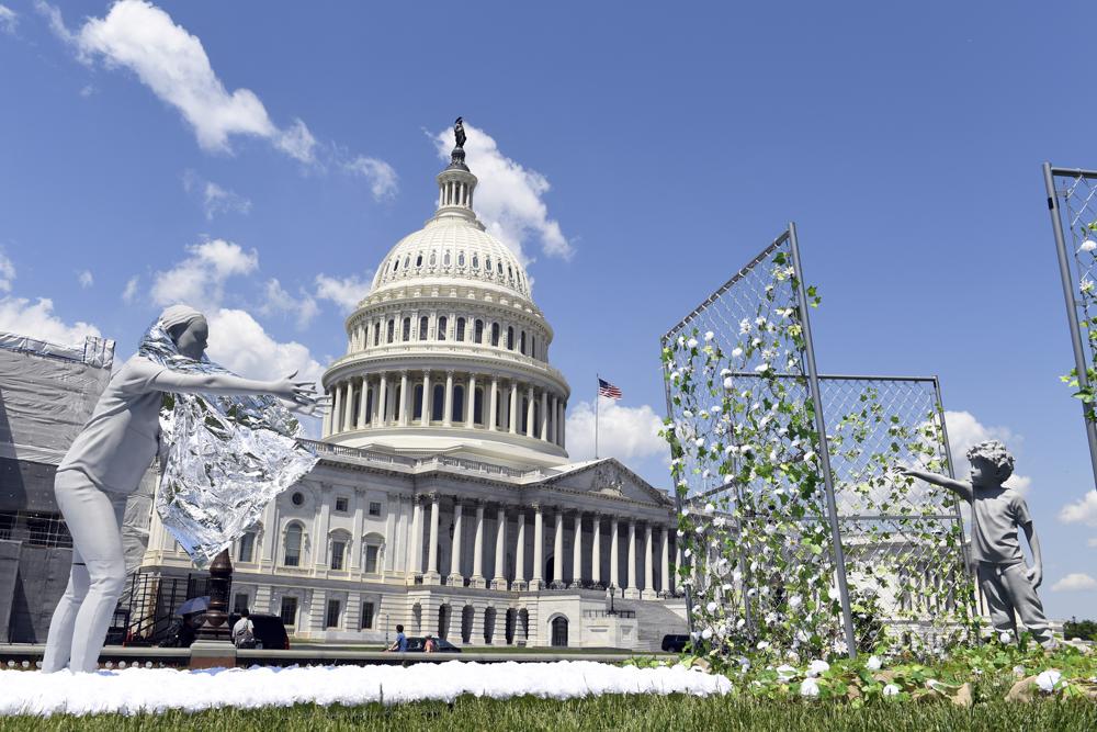 ARCHIVO - Una instalación artística ante el Capitolio de Washington muestra a una madre tendiendo la mano a su hijo, para marcar el primer aniversario de la política de "tolerancia cero" de separación de familias en la frontera introducida por el gobierno de Donald Trump, el martes 7 de mayo de 2019. Las estancadas negociaciones del gobierno de Estados Unidos sobre compensación a las familias separadas en la frontera han planteado nuevas amenazas de extorsión en Centroamérica. No está claro que las familias vayan a recibir dinero. (AP Foto/Susan Walsh, Archivo)