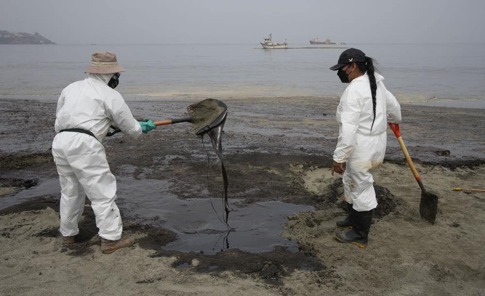 Trabajadores, vestidos con trajes protectores, continúan limpiando la playa Conchitas contaminada con petróleo, en Ancón, Perú, el jueves 20 de enero de 2022. El derrame de petróleo en la costa peruana fue causado por las olas de una erupción de un volcán submarino en el Nación del Pacífico Sur de Tonga.  (Foto AP/Martin Mejia)