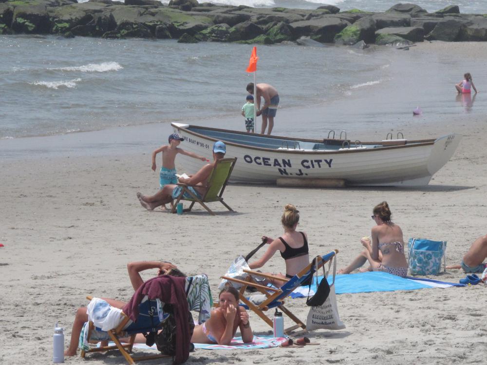 This July 8, 2021, photo shows people on the beach in Ocean City, N.J. On Nov. 4, 2021, a coalition of environmental and faith-based groups began a campaign to drum up support for offshore wind projects in New Jersey, particularly in places like Ocean City, where opposition to such projects has been vocal. (AP Photo/Wayne Parry)