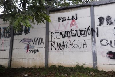 Una pared pintada con graffitis con un mensaje que alguna vez decía en español: "Resiste Nicaragua", fue pintado por otro que ahora dice "Viva la revolución" en Managua, Nicaragua, el jueves 17 de junio de 2021. Recientemente el gobierno del presidente Daniel Ortega detuvo a 13 líderes de la oposición, incluidos cuatro aspirantes a la presidencia para las elecciones del 7 de noviembre. (AP Foto/Miguel Andrés)