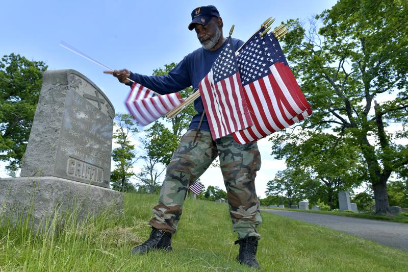 Bob Workman of Boston, a retired Marine Gunnery Sgt., and past commander of the Boston Police VFW, replaces flags at veteran's graves ahead of Memorial Day on Thursday, May 27, 2021, in the Fairview Cemetery in Boston. After more than a year of isolation, American veterans are embracing plans for a more traditional Memorial Day. After more than a year of isolation, military veterans say wreath-laying ceremonies, barbecues at local vets halls and other familiar traditions are a welcome chance for them to reconnect with fellow service members and renew solemn traditions honoring the nation's war dead. (AP Photo/Josh Reynolds)