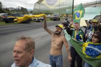 Los partidarios del presidente de Brasil, Jair Bolsonaro, protestan por su pérdida de reelección al costado de la carretera que conduce al Aeropuerto Internacional de Sao Paulo-Guarulhos, en Guarulhos, Brasil, el martes 1 de noviembre de 2022. (AP Foto/Victor R. Caivano)