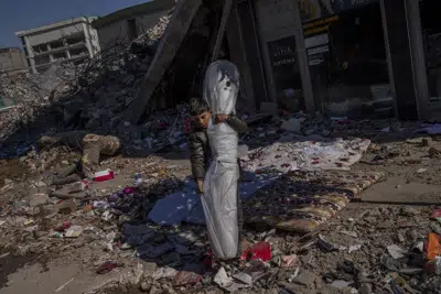 El hijo de la familia Sonmez recupera una alfombra de la vivienda tras el potente sismo que golpeó Kahramanmaras, Turquía, el 17 de febrero de 2023. (AP Foto/Bernat Armangué)