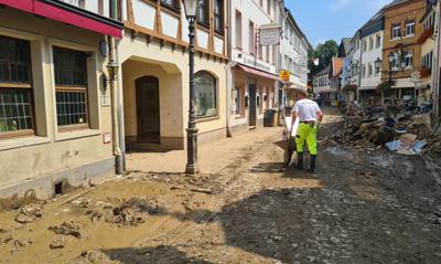 Un hombre despeja escombros con una carretilla a través de las calles del pueblo afectado por la inundación Ahrweiler, Alemania, el viernes 23 de julio de 2021. (AP Foto/Frank Jordans)