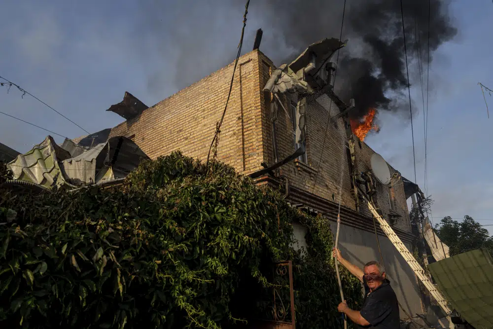 Un hombre trata de apagar un incendio en una casa dañada por un bombardeo ruso, en Jersón, Ucrania, el 9 de junio de 2023. Las masivas inundaciones causadas por la destrucción de la represa de Kajovka el 6 de junio han arrasado pueblos situados río abajo en ambas orillas del Dniéper, en la región de Jersón, que está en la línea del frente de la guerra. Rusia y Ucrania se acusan mutuamente de provocar el colapso. (AP Foto/Evgeniy Maloletka)