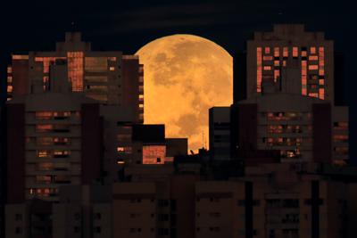 La Luna luce cubierta parcialmente por edificios en Brasilia, Brasil, el miércoles 26 de mayo de 2021 al comenzar un eclipse lunar total. Fue el primer eclipse en más de dos años y coincidió con una superluna. (AP Foto/Eraldo Peres)