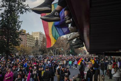 Los pies de los adolescentes cuelgan de un balcón mientras ven pasar el desfile anual del Orgullo Gay en Santiago, Chile, el sábado 25 de junio de 2022. (Foto AP/Esteban Félix)