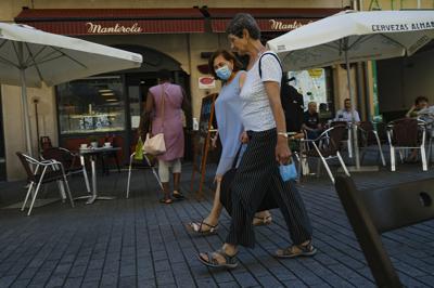 Dos mujeres caminan cerca de un bar en Pamplona, norte de España, el 5 de julio de 2021. (AP Foto/Alvaro Barrientos)