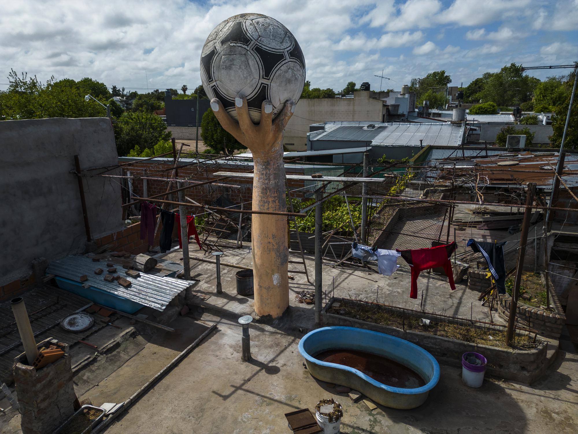 Un tanque de agua que parece una mano grande que sostiene una pelota de fÃºtbol se encuentra en el techo de una casa que recuerda el famoso gol con la mano de Diego Maradona contra Inglaterra en la Copa del Mundo de 1986 en el barrio La Cumbre, en las afueras de La Plata, Argentina, martes 18 de octubre de 2022. (AP Foto/Rodrigo Abd)