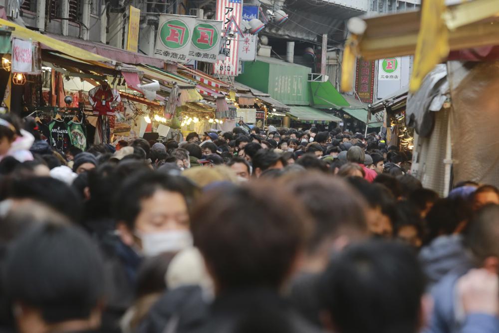 Personas que usan mascarillas para protegerse contra el coronavirus caminan en una calle para sus compras de fin de año en Tokio el viernes 31 de diciembre de 2021 (AP Photo / Koji Sasahara).