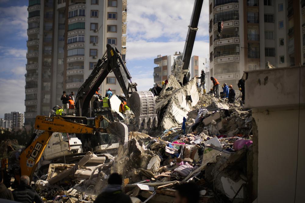 Emergency rescue members search for people in a destroyed building in Adana, Turkey, Tuesday, Feb. 7, 2023. Rescuers raced Tuesday to find survivors in the rubble of thousands of buildings brought down by a powerful earthquake and multiple aftershocks that struck eastern Turkey and neighboring Syria. (AP Photo/Francisco Seco)