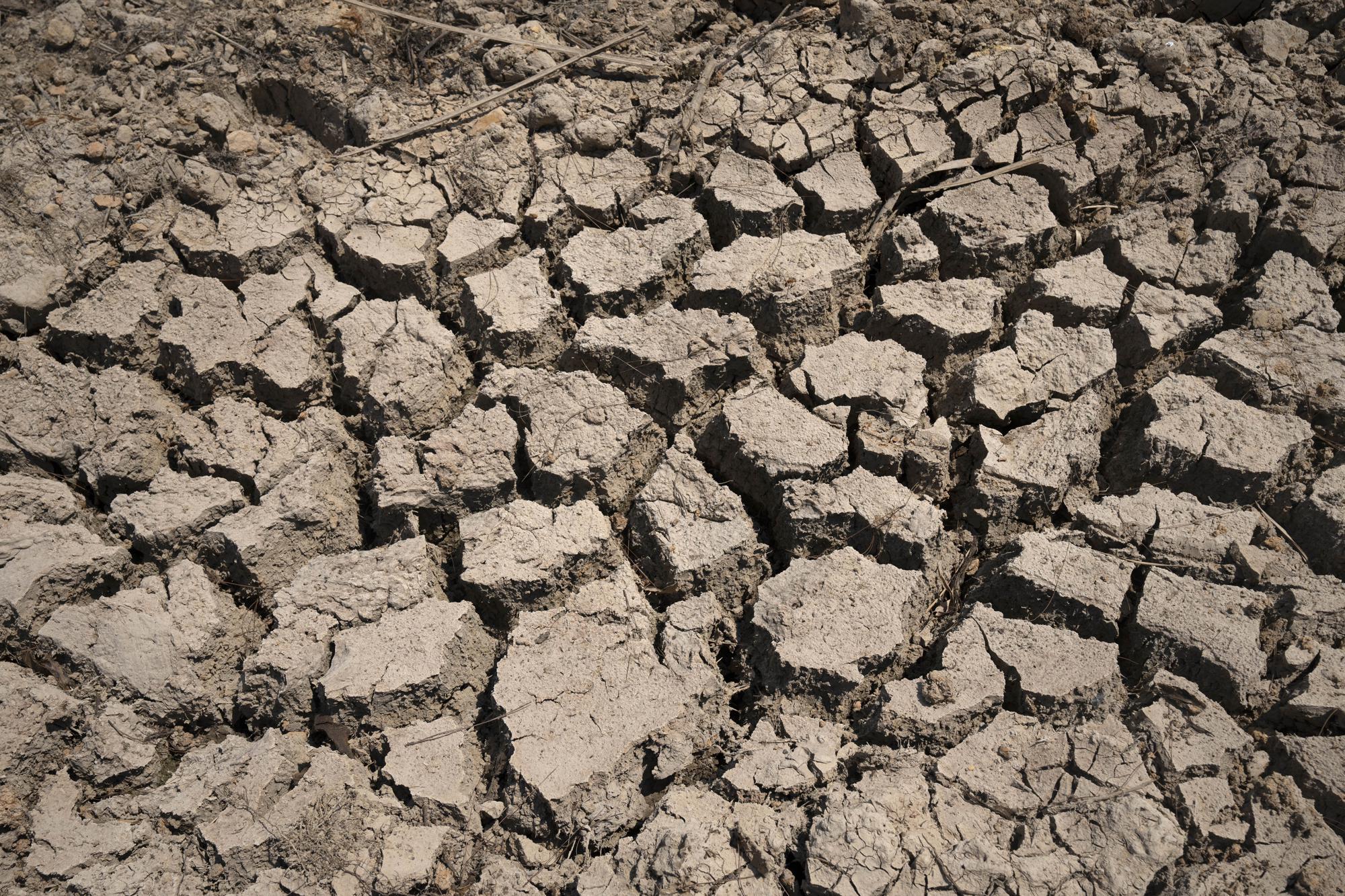 FILE - Cracked dry mud is seen in a community reservoir that ran nearly empty after its retaining wall started to leak and hot weather and drought conditions accelerated the loss of water Longquan village in southwestern China's Chongqing Municipality, Saturday, Aug. 20, 2022. The very landscape of Chongqing, a megacity that also takes in surrounding farmland and steep and picturesque mountains, has been transformed by an unusually long and intense heat wave and an accompanying drought. (AP Photo/Mark Schiefelbein, File)