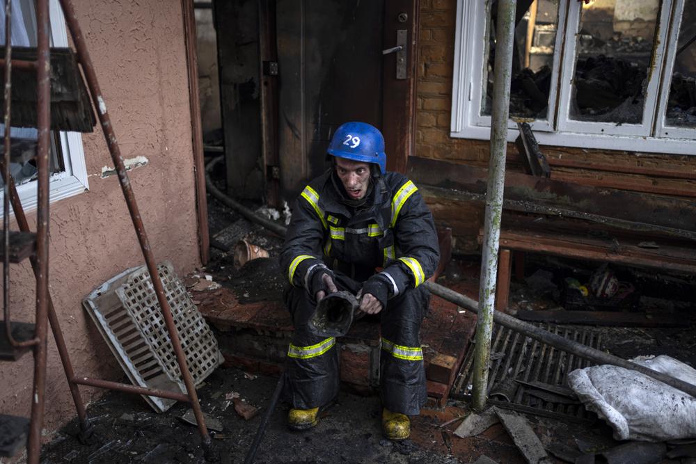 Un bombero ucraniano se toma un descanso para extinguir un incendio dentro de una casa destruida por los bombardeos en Kiev, Ucrania, el miércoles 23 de marzo de 2022. La administración de la ciudad de Kiev dice que las fuerzas rusas bombardearon la capital ucraniana durante la noche y la madrugada del miércoles, en los distritos de Sviatoshynskyi. y Shevchenkivskyi, dañando edificios.  (Foto AP/Rodrigo Abd)