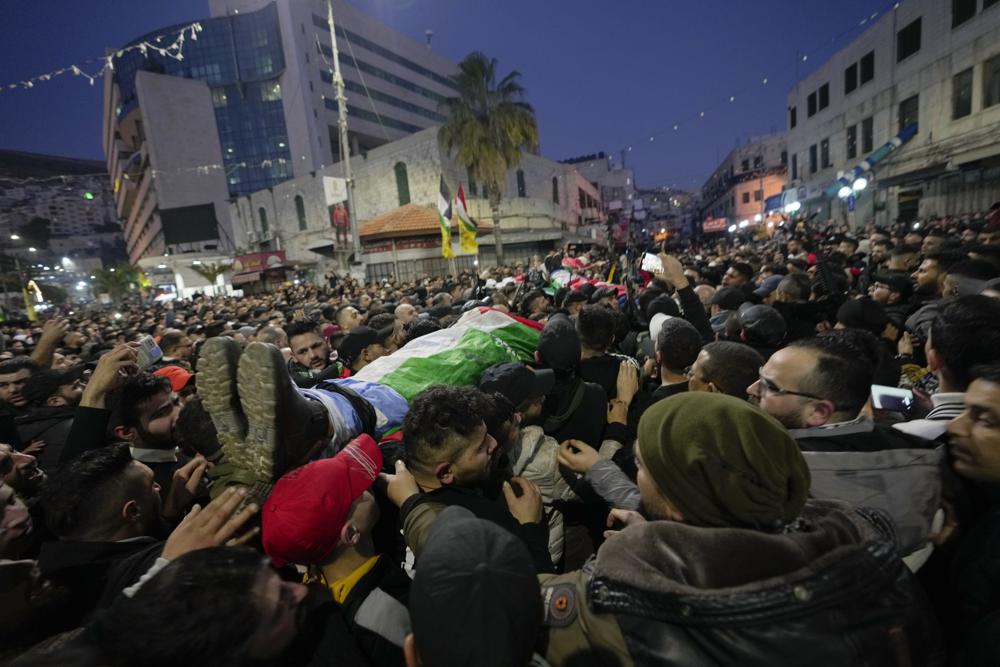 Mourners carry the bodies of three Palestinian who were killed by Israeli forces, during their funeral in the occupied West Bank city of Nablus, Tuesday, Feb. 8, 2022. Israel said it killed three Palestinian militants in Nablus who had been responsible for recent shooting attacks. (AP Photo/Majdi Mohammed)