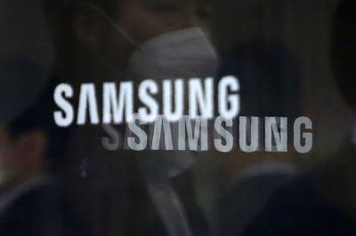Archivo - Empleados reflejados en las ventanas de una puerta giratoria con logotipos de Samsung Electronics Co. en su oficina en Seúl, Corea del Sur. (AP Foto/Ahn Young-joon, Archivo)