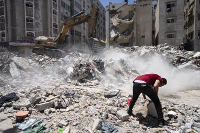 Equipo pesado de construcción es utilizado para revisar entre los escombros de un edificio destruido por un ataque aéreo durante los enfrentamientos entre el grupo Hamas, que gobierna Gaza, e Israel, el jueves 27 de mayo de 2021 en Ciudad de Gaza. (AP Foto/John Minchillo)