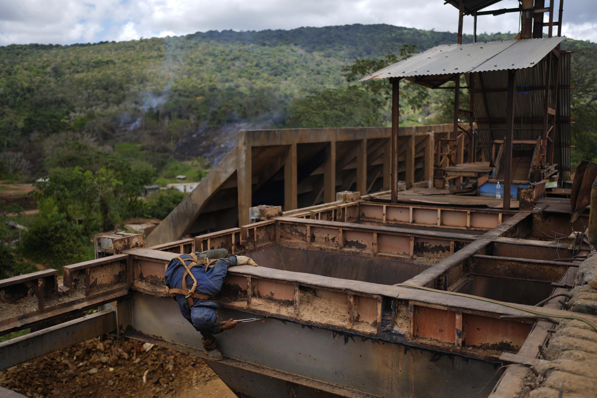 Un trabajador retira placas de hierro de un área no utilizada de una mina de oro subterránea para reutilizarlas para máquinas de fresado, en El Callao, estado de Bolívar, Venezuela, el viernes 28 de abril de 2023. (Foto AP/Matias Delacroix)