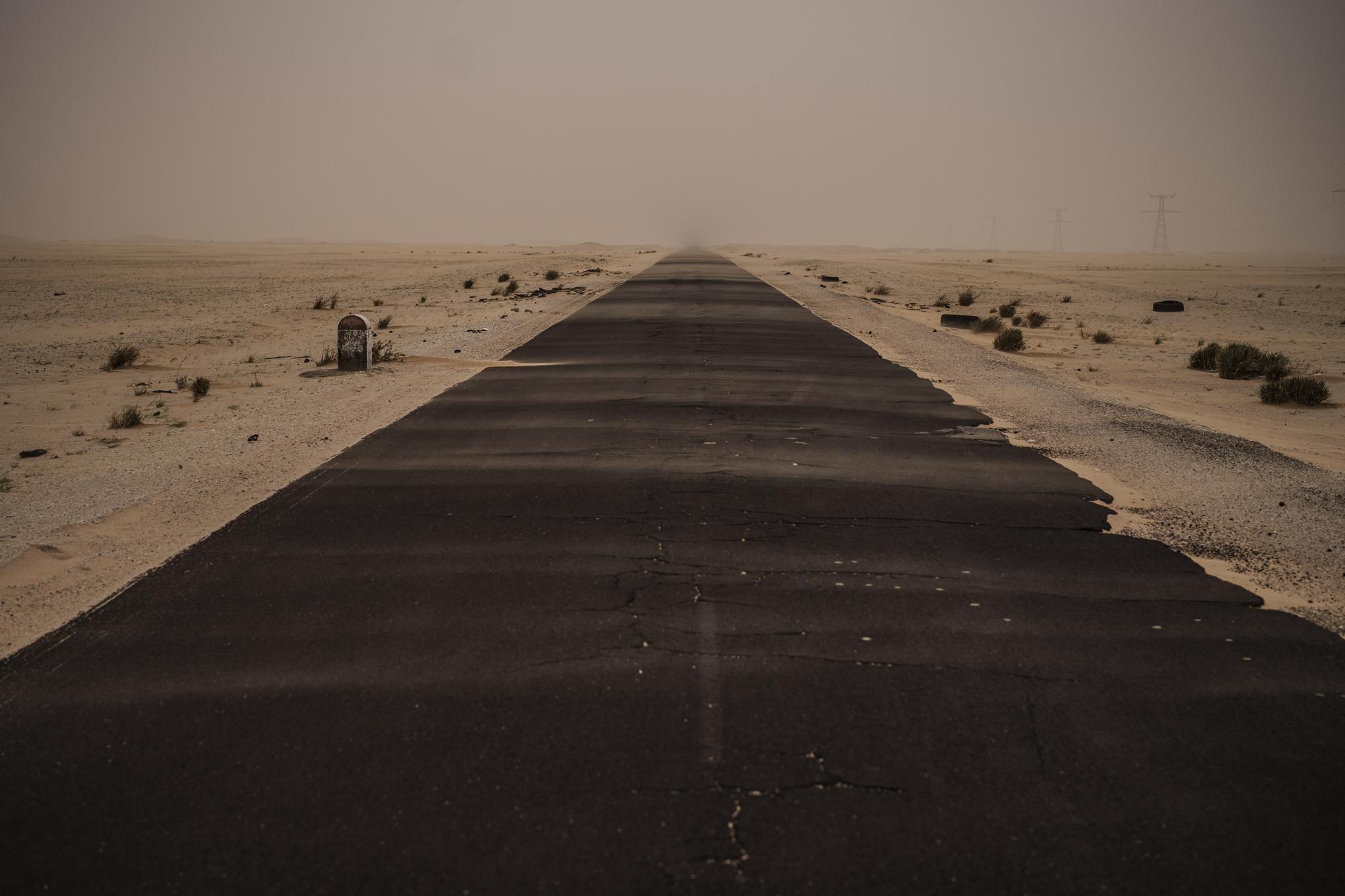 Una pista de asfalto cubierta parcialmente de arena cerca de Nuadibú, Mauritania, el 2 de diciembre de 2021. (AP Foto/Felipe Dana)