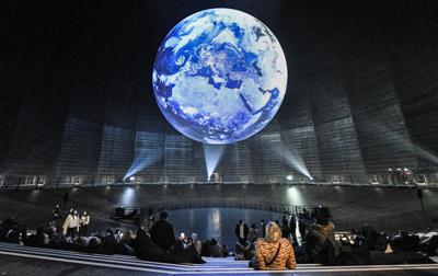 En esta imagen de archivo, tomada el 7 de octubre de 2021, visitantes observan una instalación gigante de la tierra en la exposición "El paraíso frágil", dentro del antiguo almacén de gas "Gasometer", en Oberhausen, Alemania. (AP Foto/Martin Meissner, archivo)