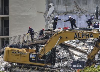 Personal especializado busca a sobrevivientes el sábado 26 de junio de 2021 entre los restos del edificio de apartamentos Champlain Towers, de 12 niveles, que el jueves se vino abajo parcialmente, en la localidad de Surfside, en Florida. (Al Diaz/Miami Herald vía AP)