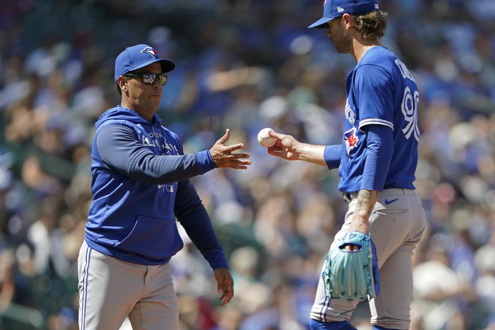 El lanzador de los Azulejos de Toronto Adam Cimber (derecha) es sacado por el manager Charlie Montoyo durante el juego contra los Marineros de Seattle, el 10 de julio de 2022. (AP Foto/Ted S. Warren)