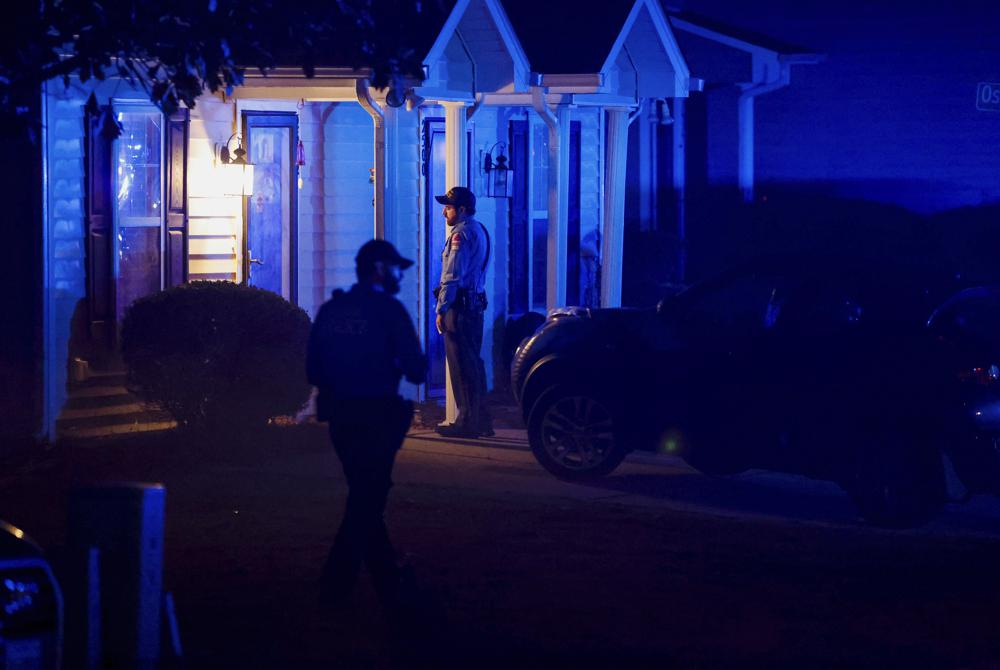Raleigh Police officers walk door to door checking on residents in the Hedingham neighborhood and Neuse River Trail area in Raleigh, N.C. Thursday, Oct. 13, 2022. A shooter opened fire along a walking trail in North Carolina’s capital city on Thursday, killing five people before leading police on an hours long manhunt that forced residents across multiple neighborhoods to take shelter in their homes. (Travis Long/The News & Observer via AP)