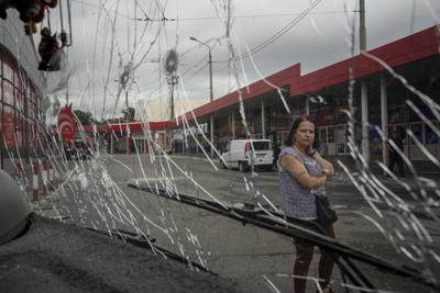 Una mujer mira un trolebús dañado por los bombardeos rusos en el mercado de Barabashovo en Jarkiv, Ucrania, el jueves 21 de julio de 2022. (Foto AP/Evgeniy Maloletka)