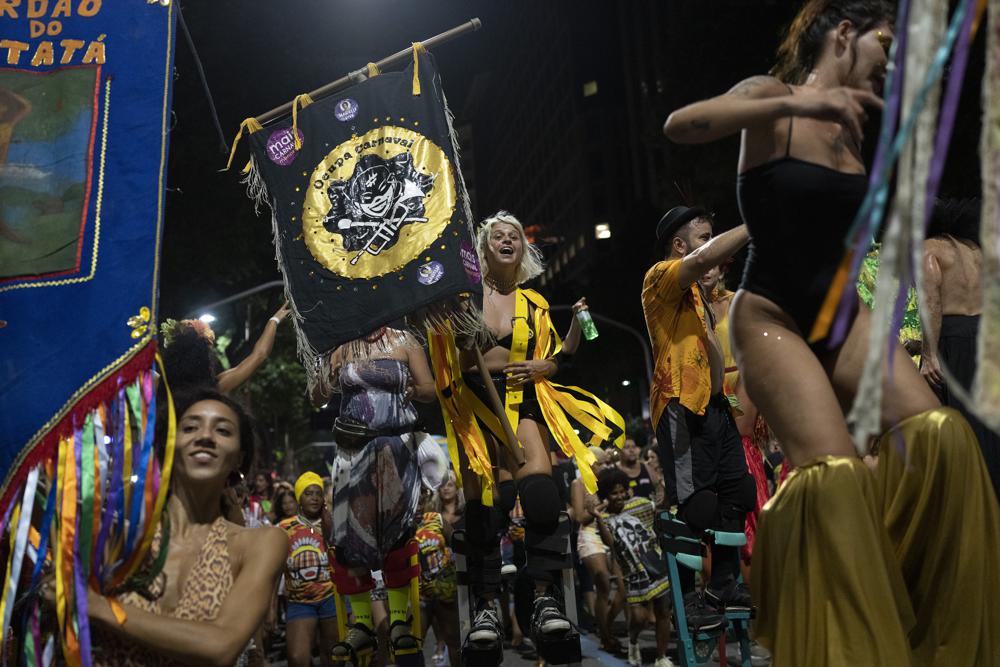 Revellers of street parties known as blocos, dance during a protest against restrictions by city officials in Rio de Janeiro, Brazil, Wednesday, April 13, 2022. City Hall has banned the street parties during Carnival celebrations, which were delayed by almost two months due to the pandemic. (AP Photo/Silvia Izquierdo)