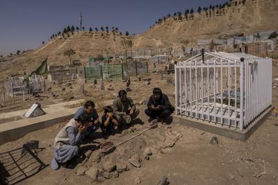ARCHIVO - En esta foto de archivo del 13 de setiembre de 2021, la familia Ahmadi reza junto a las tumbas de sus 10 familiares, incluidos siete niños, muertos por el ataque de un dron estadounidense, en Kabul, Afganistán. (AP Foto/Bernat Armangue, File)