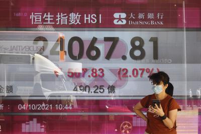 Una persona frente a una cartelera financiera en  Hong Kong el 4 de octubre de 2021.  (AP Photo/Vincent Yu)